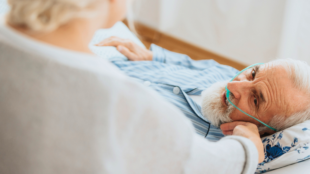 Elderly woman caressing the cheek of her dying husband