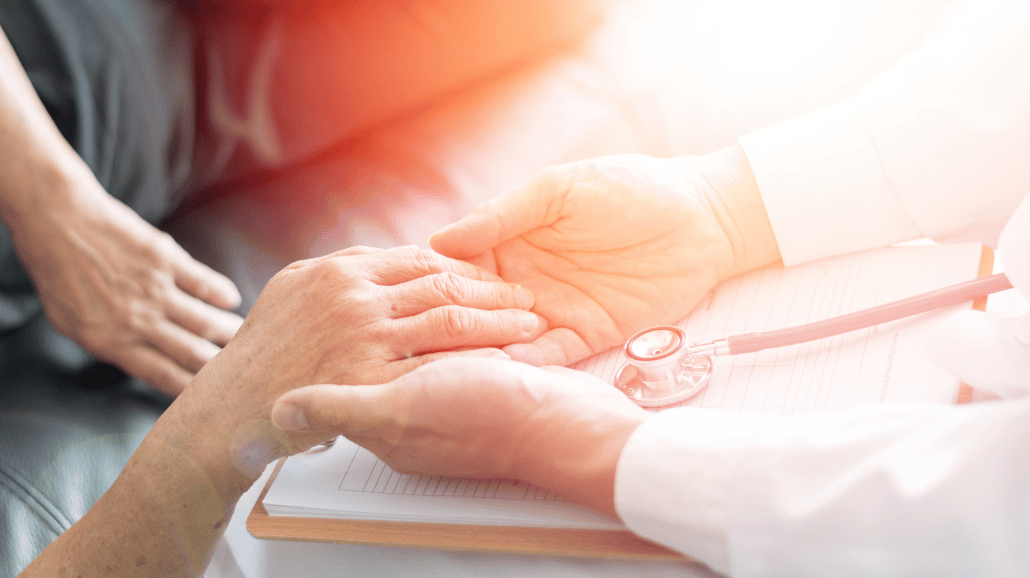 Hospice nurse holding the hand of a patient