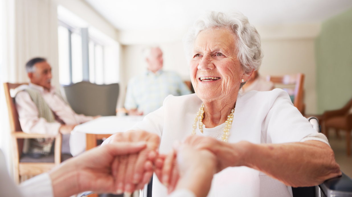 Senior woman in a nursing home, holding the hands of a nurse