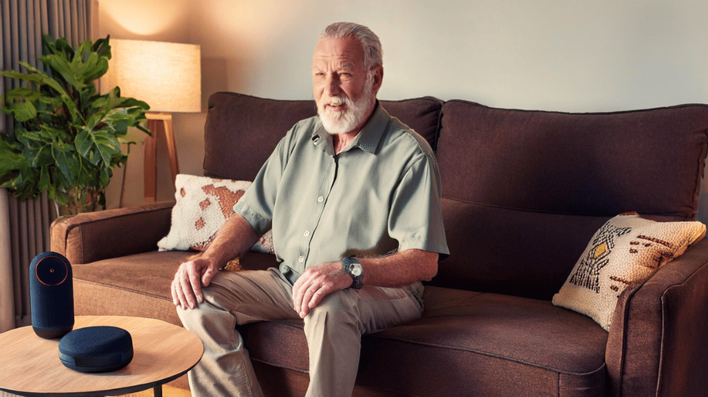 Blog Covers – 2025-02-06T134239.061 Senior man sitting on a couch with a voice-activated device onthe coffee table