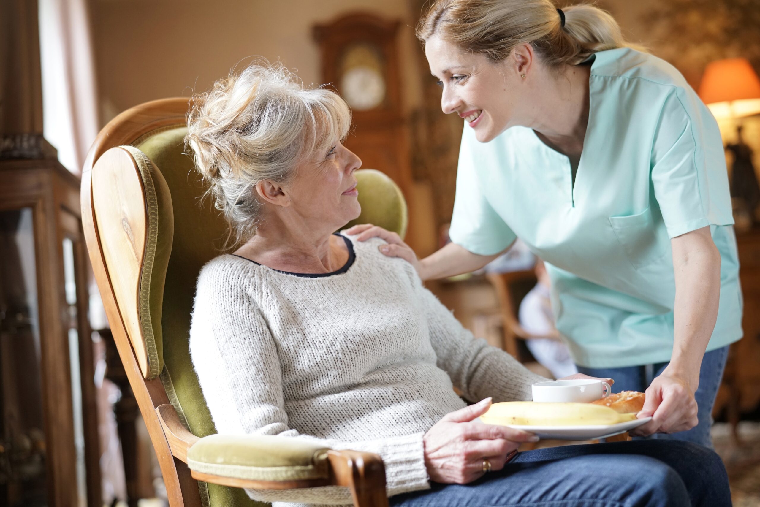 Caregiver giving an elderly woman a plate of breakfast