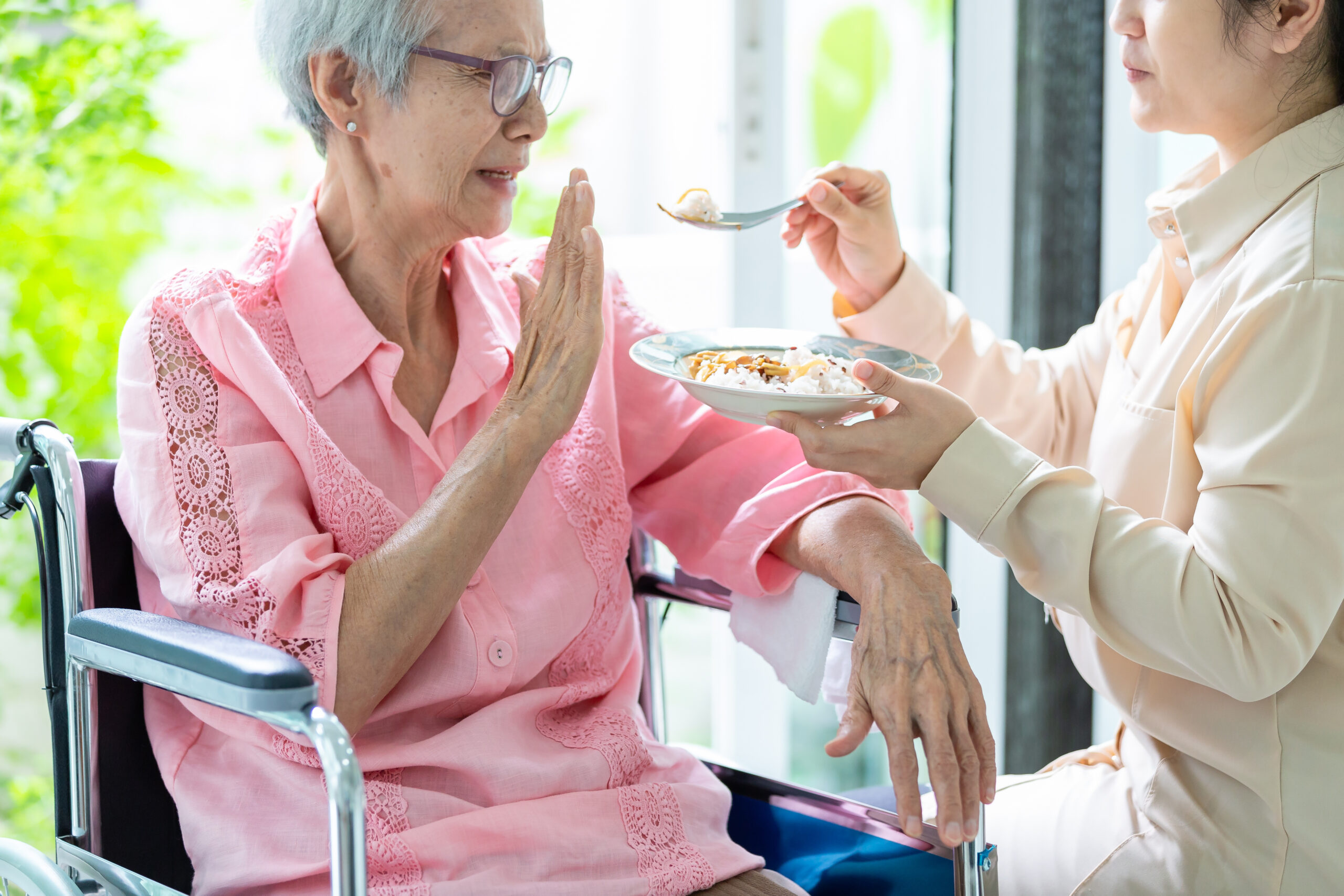 AdobeStock_272810431 Senior woman refusing to eat food from her adult woman
