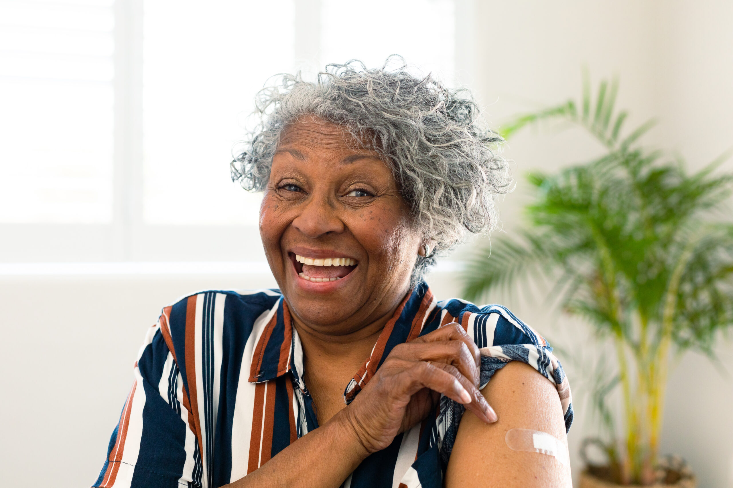 Happy senior african american woman with plaster on arm looking Happy senior african american woman with bandage on arm