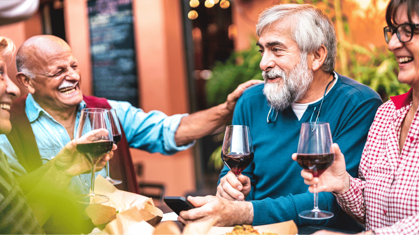 Two senior couples eating outdoors at a restaurant and drinking wine