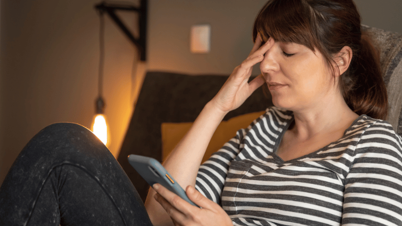 Family caregiver reading her phone and putting her hand over her eyes