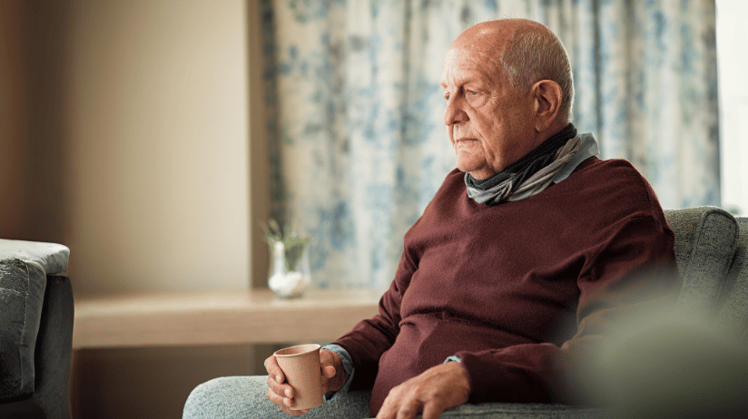 Blog20Covers20-202023-11-02T103134.798 Senior man sitting in a chair holding a cup of water, looking depressed