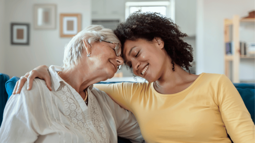 Blog20Covers20-202023-12-06T153735.331 Senior woman sitting on a couch hugging her adult daughter
