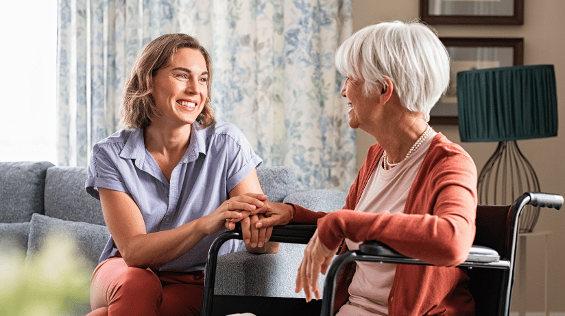 Caregiver holding the hand of a senior woman in a wheelchair
