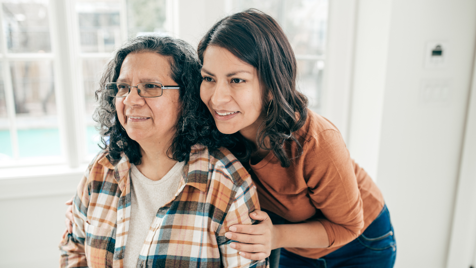 Senior woman wearing flannel and smiling in a mirror with her adult daughter