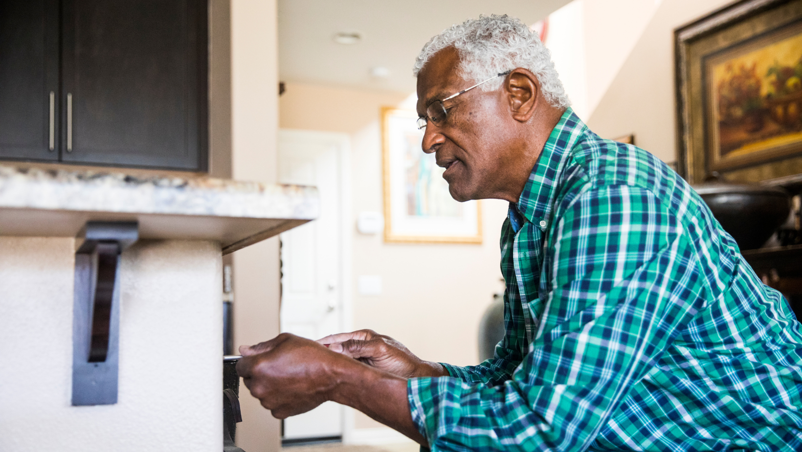 Senior man fixing something in his kitchen