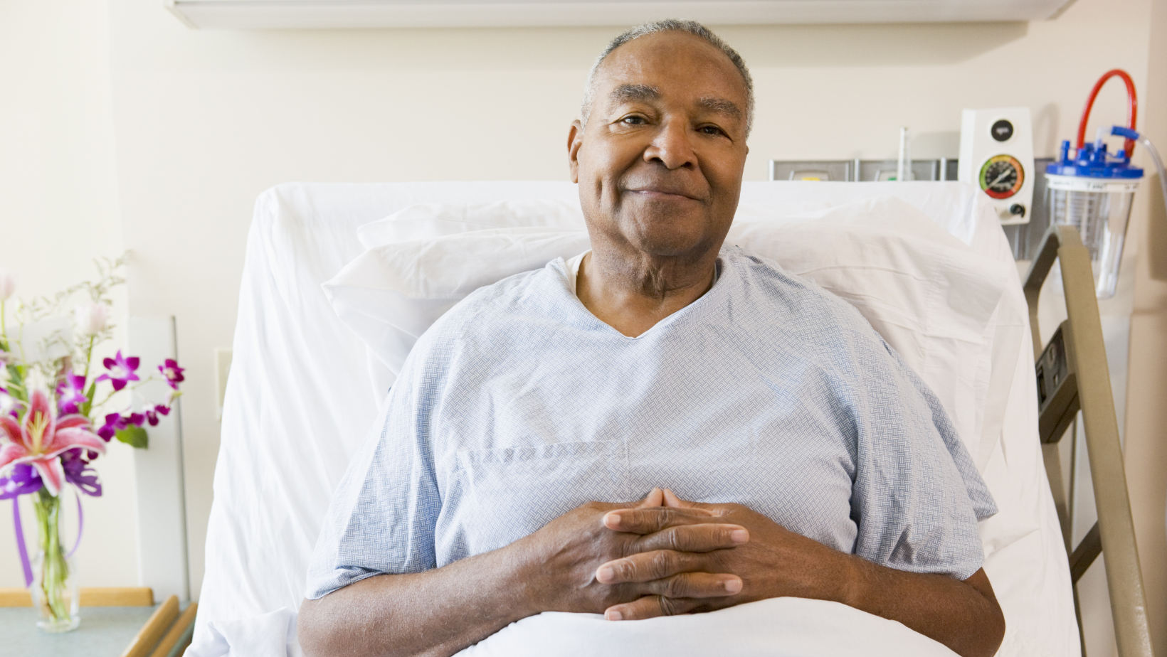 Senior man smiling while sitting up in a hospital bed