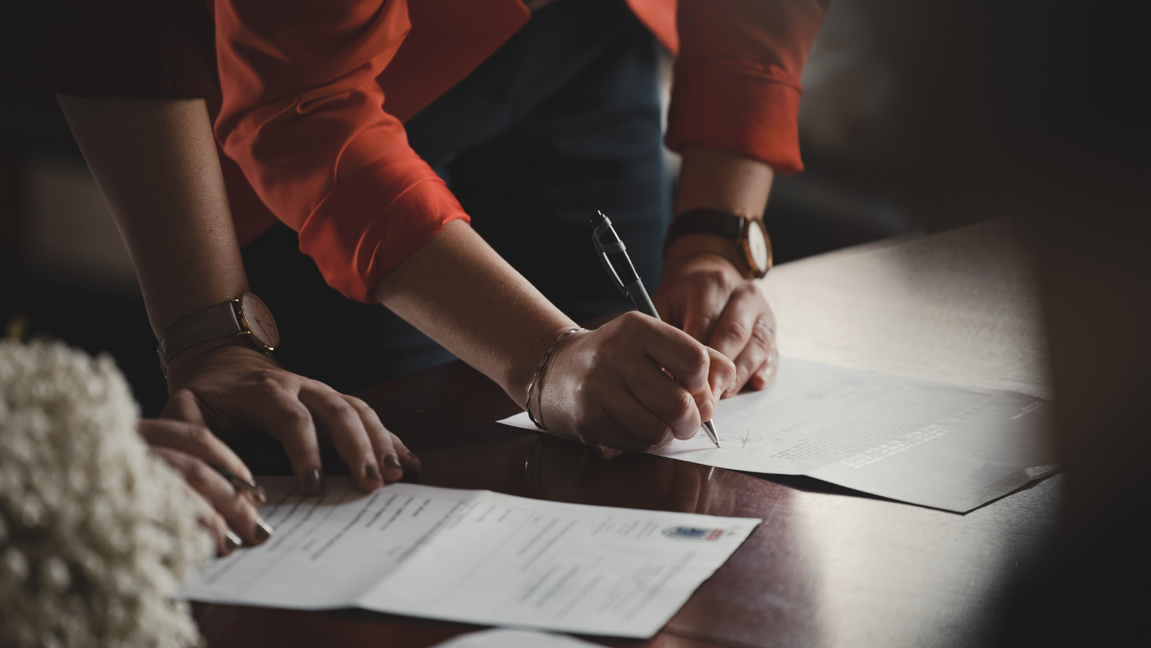 Couple signing paperwork in a darkly lit room
