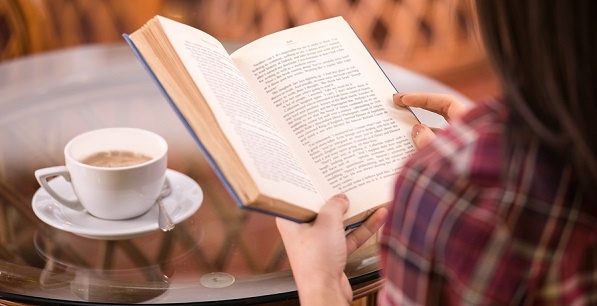 Woman reading a book while drinking coffee