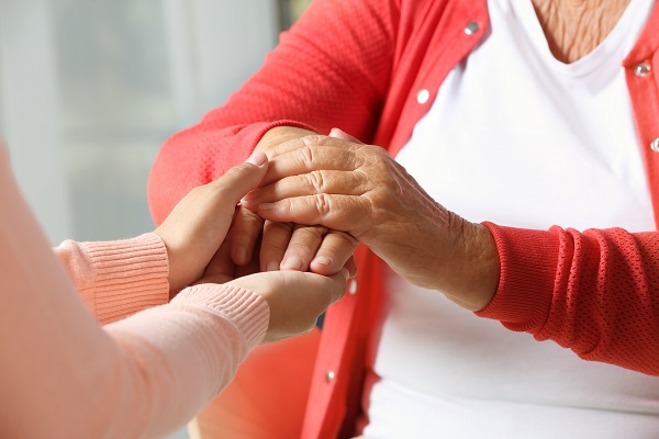 Helping hands on blurred background, closeup. Elderly care concept
