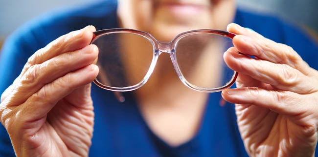 Edlerly_Woman_Holding_Eyeglasses-LR Elderly woman holding a pair of glasses