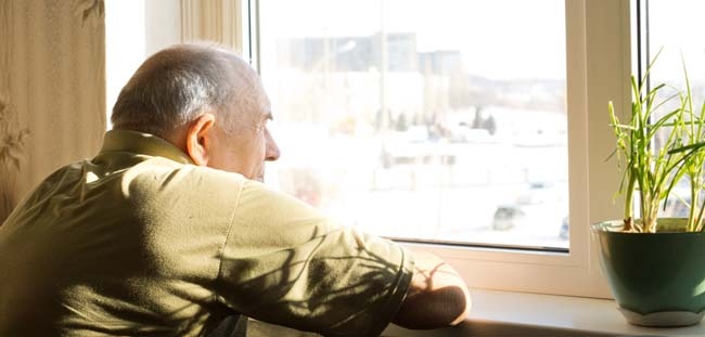 Elderly man looking out the window