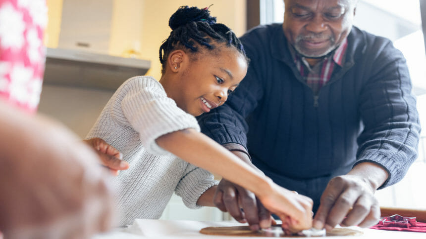 Elderly man making cookies with his granddaughter