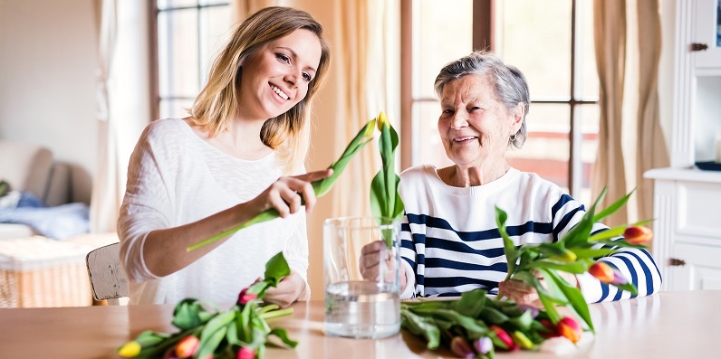 Senior woman arranging flowers with her adult daughter