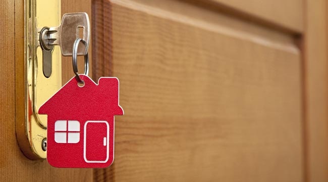 Wooden door with a key in the lock and a house keychain