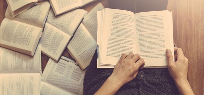 Woman reading a book and books around her