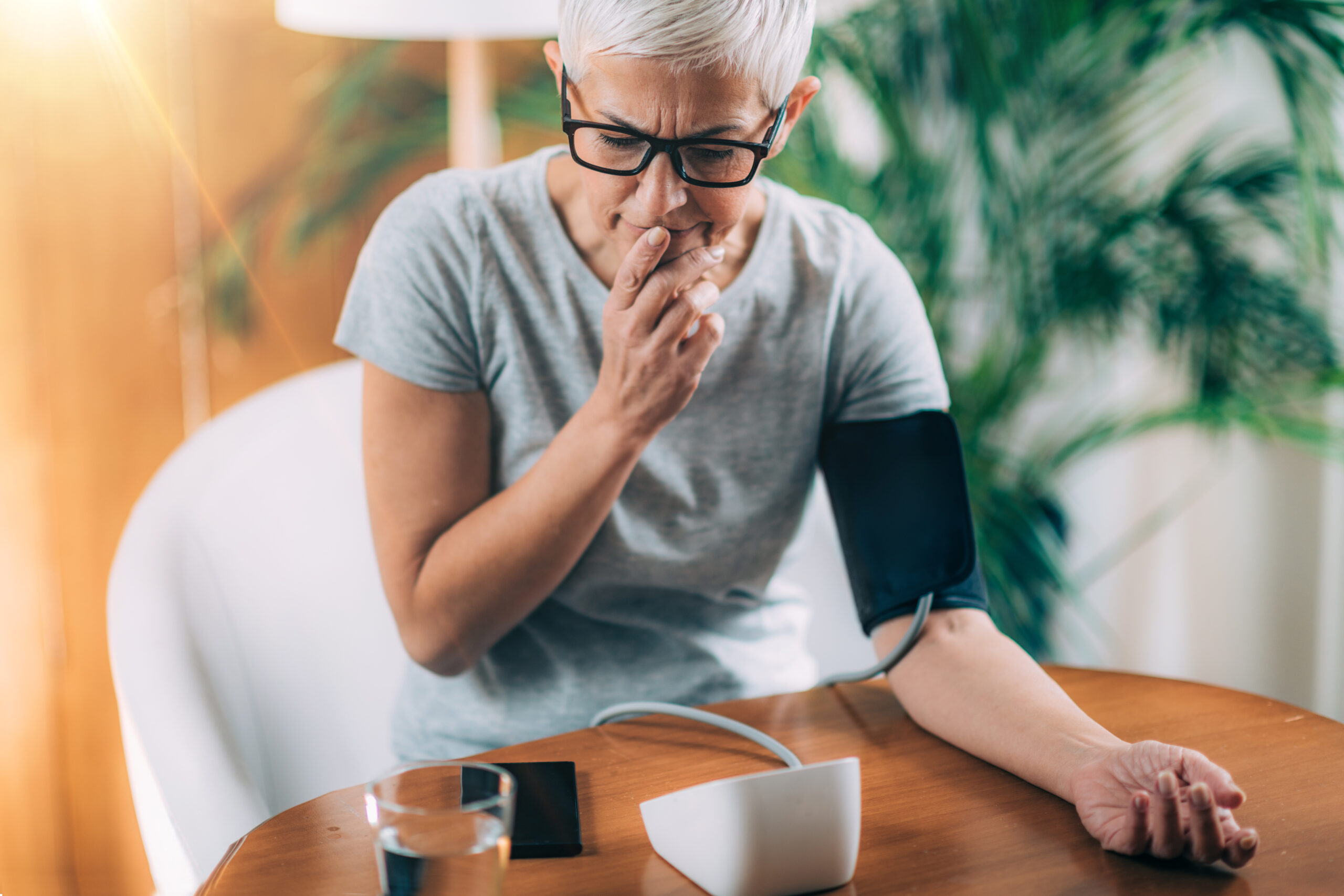 Digital Health – Blood pressure monitor combined with smart phone Woman measuring her blood pressure at home