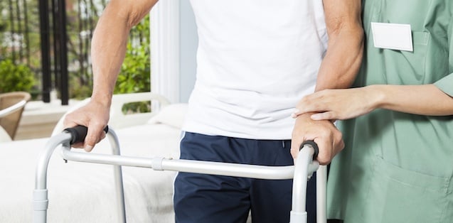 Caregiver helping a man with a walker