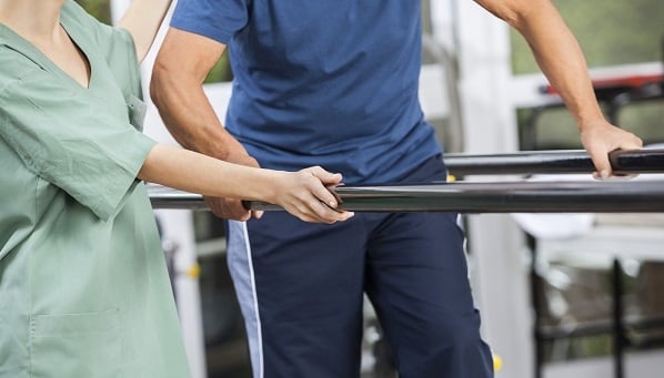 Caregiver assisting a an with physical therapy