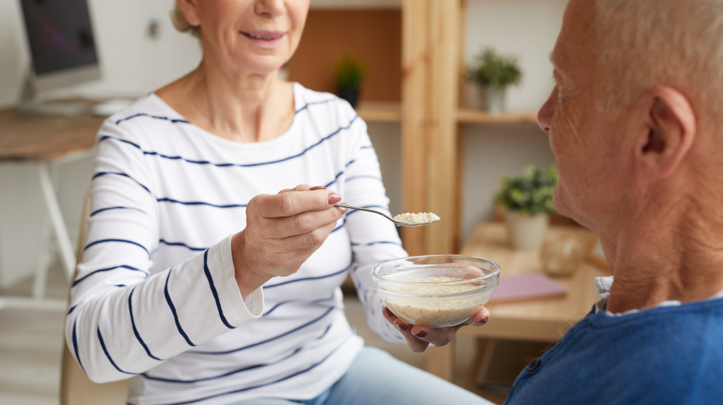 Senior woman feeding her husband oatmeal