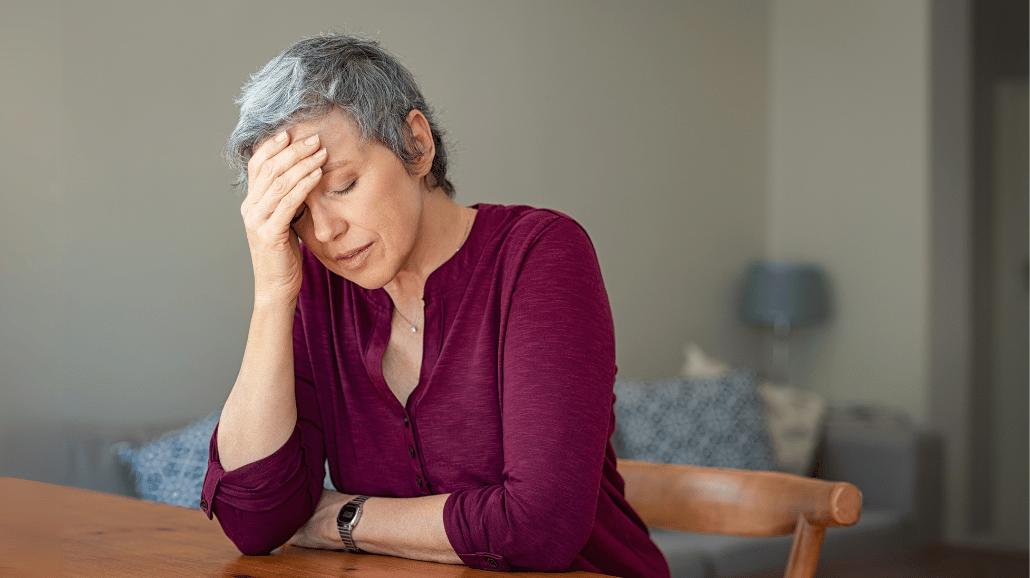Stressed elderly woman sitting at a table