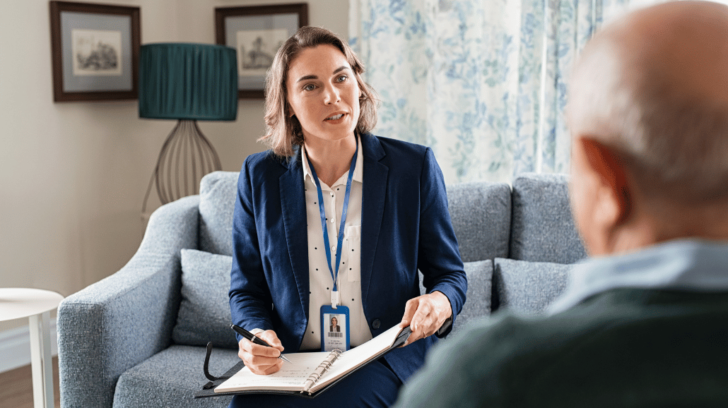 Female social worker talking to senior man in his home