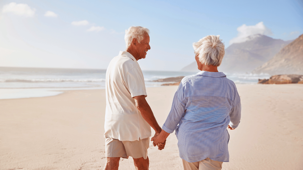 Senior couple holding hands while walking down the beach
