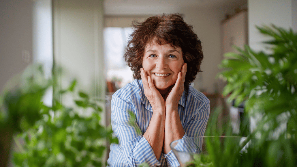 Happy senior woman sitting with hands on her face