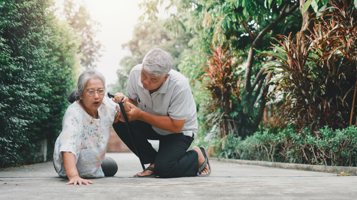 Senior woman being helped up after a fall by her husband