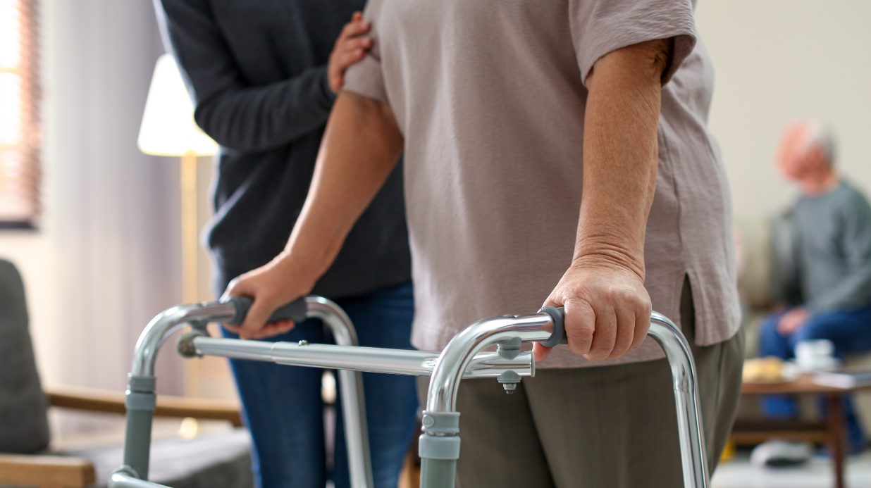 Caregiver helping a senior woman walk with a walker