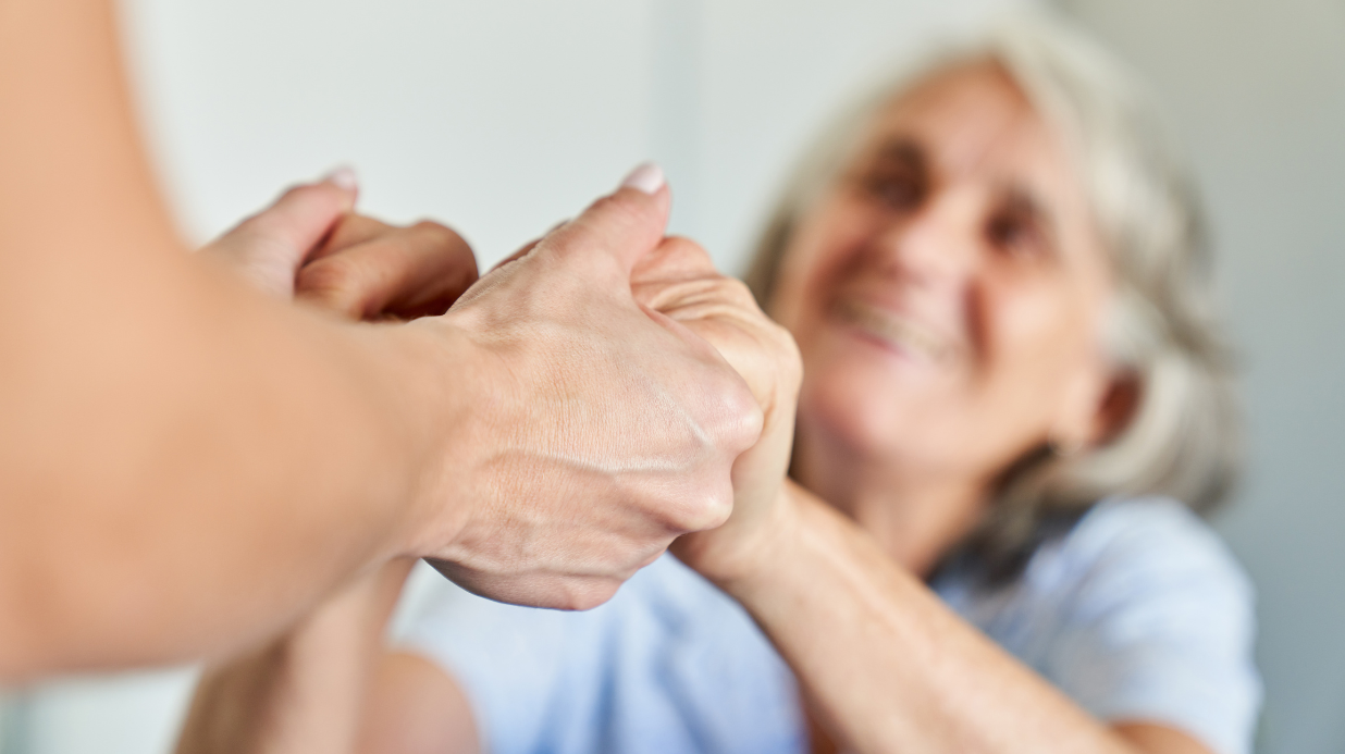 Senior woman holding the hands of a caregiver