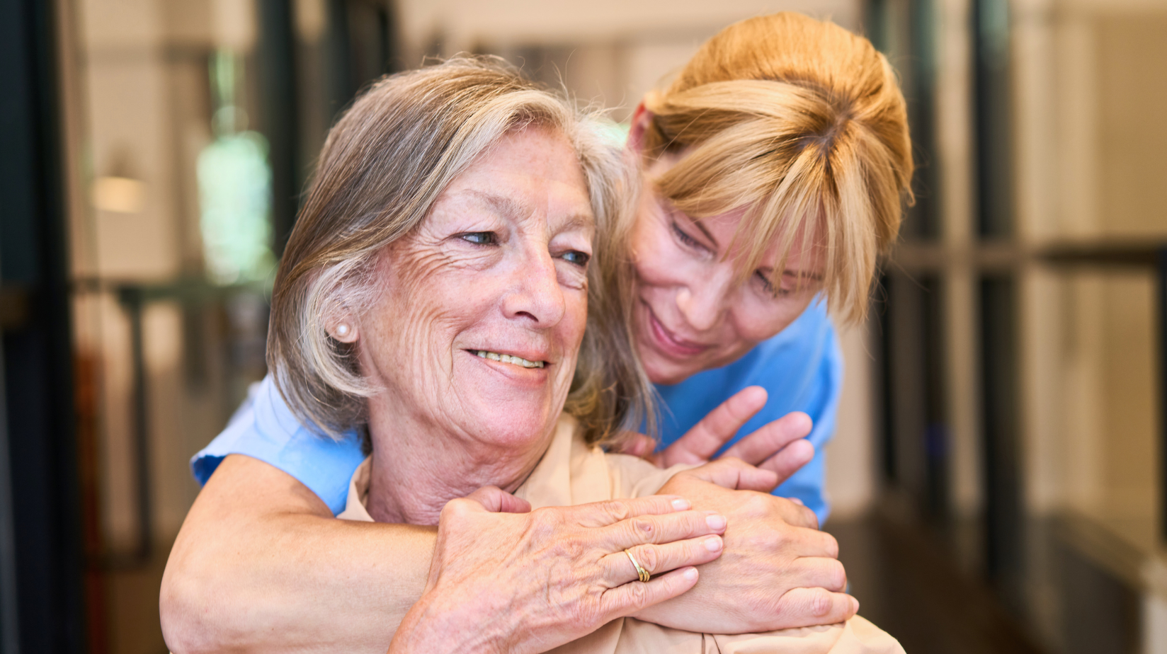 Caregiver hugging a senior woman from behind