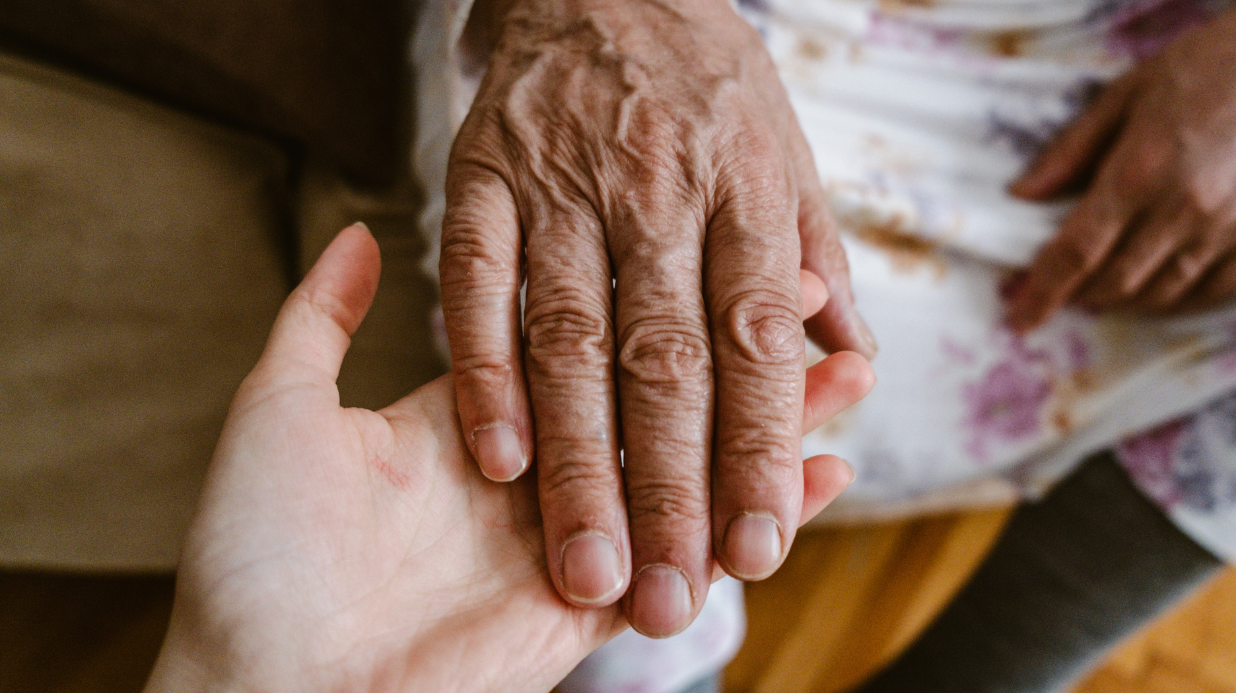 young woman's hand holding a senior woman's hand