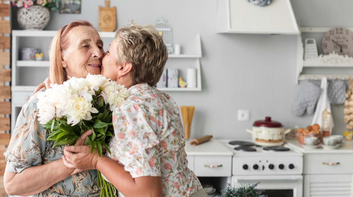Adult woman hugging her mom with dementia while giving her flowers