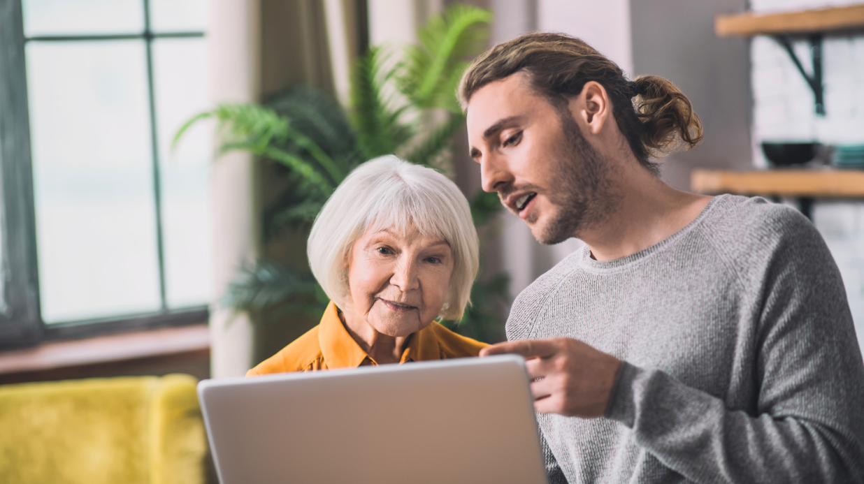 Son showing elderly mom how to use a laptop