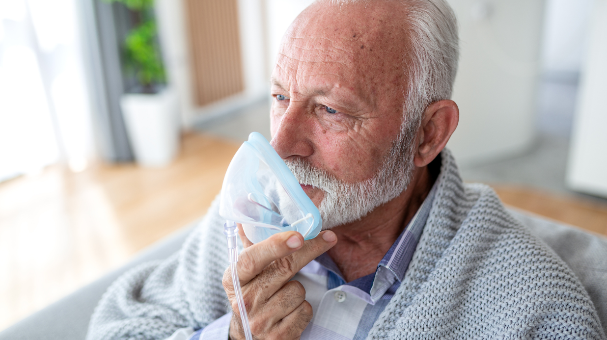 Senior man holding a nebulizer up to his face