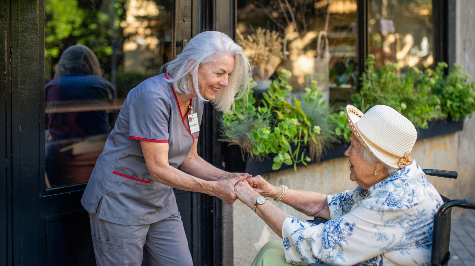 Senior woman in a wheelchair outside holding hands of her caregiver